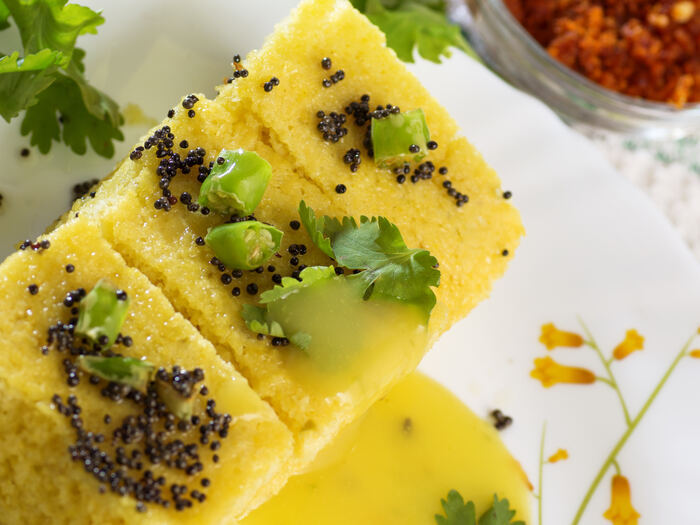 Soft steamed khaman topped with mustard seeds and coriander