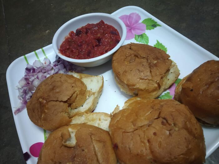 Pav bhaji rolls served with chopped onion and a side of chutney