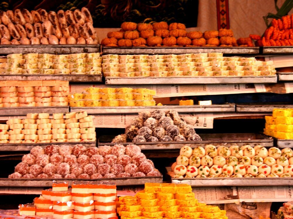 A colourful display of Gujarati sweets and snacks arranged on trays